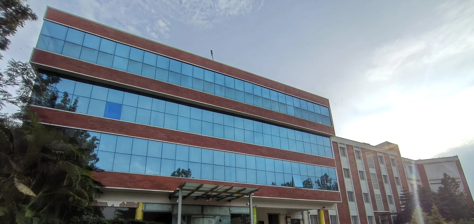 The Electronic City main building: three bands of blue glass between red-brick floors above the ground floor, with a canopy over the entrance.