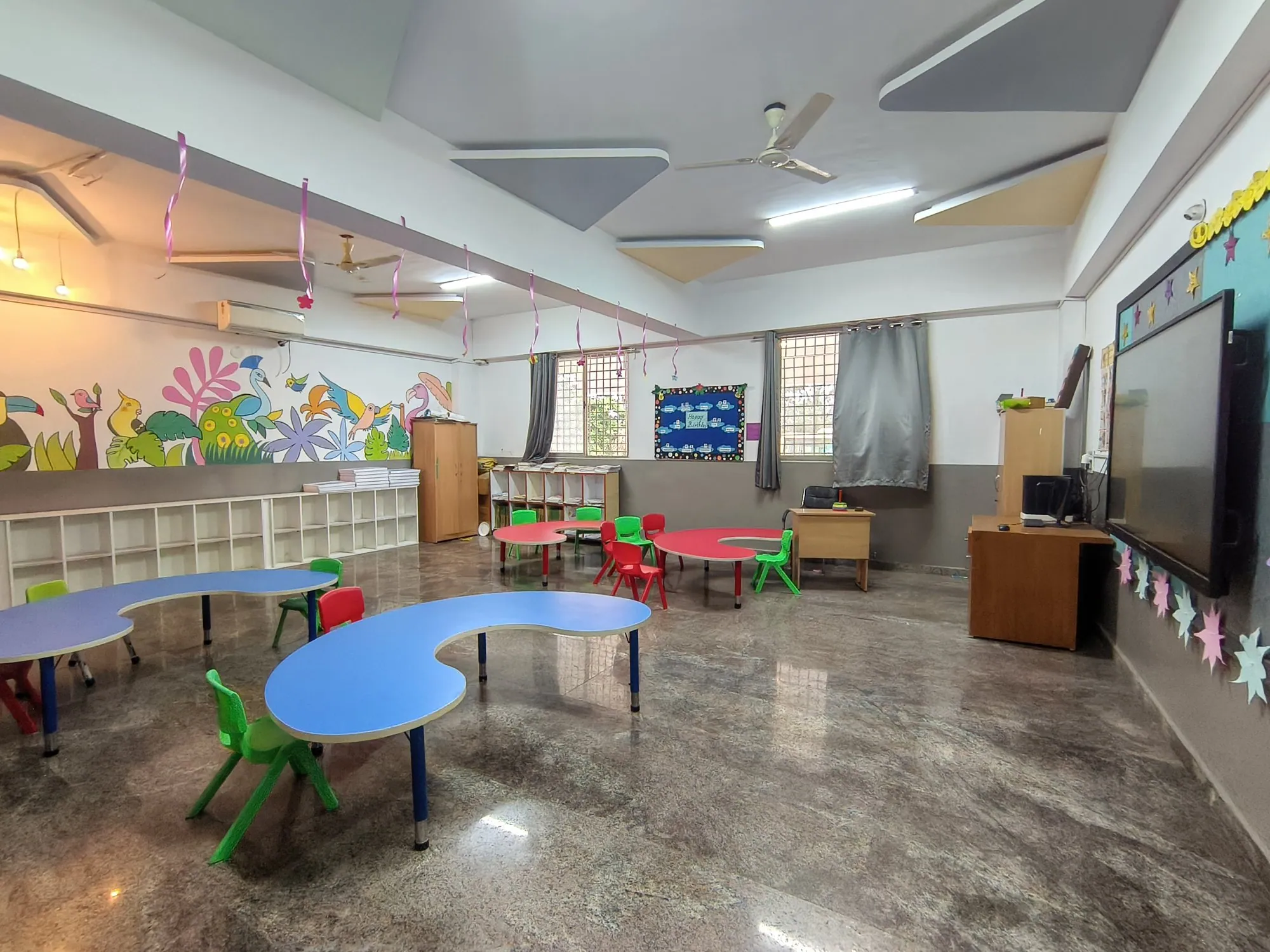 Early Years room with small tables, chairs and wall art